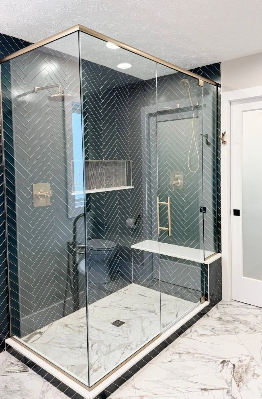Glass-enclosed shower with dark wall tile and a light mosaic floor