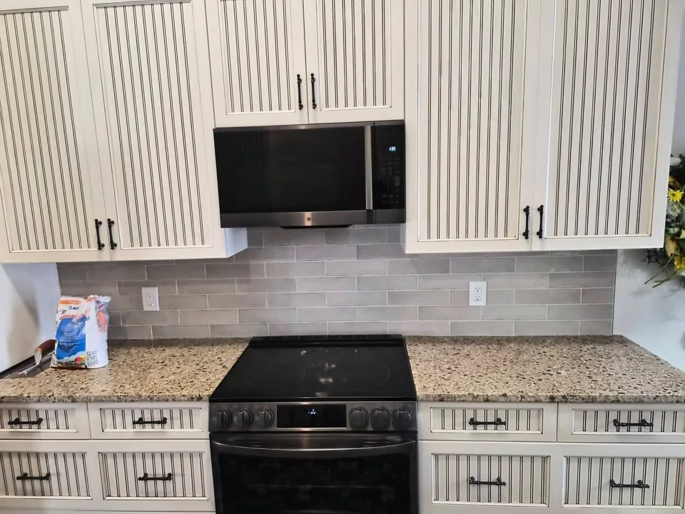 Light rectangular kitchen backsplash tile beneath white cabinets